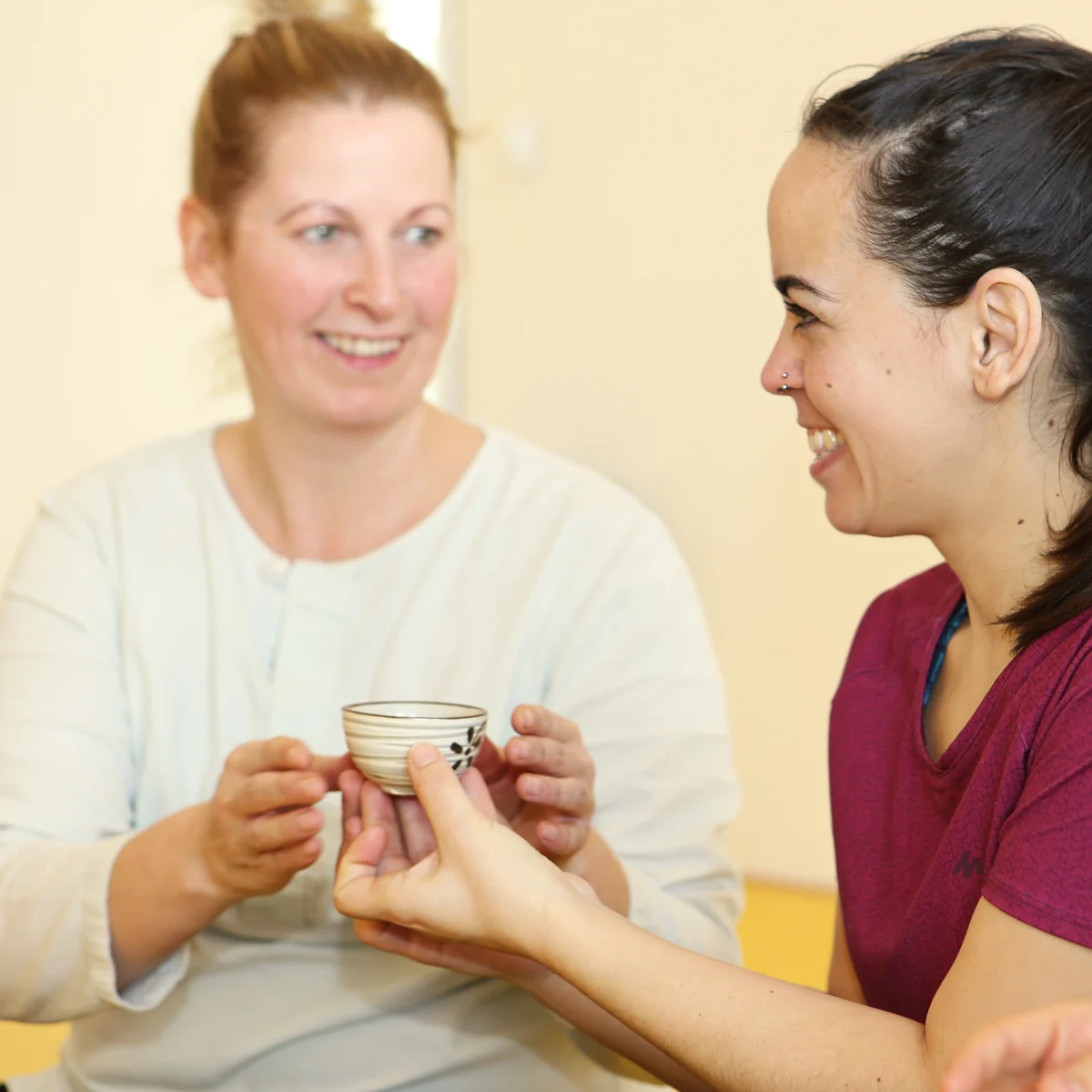 Zwei Frauen lachen miteinander im Yogastudio.