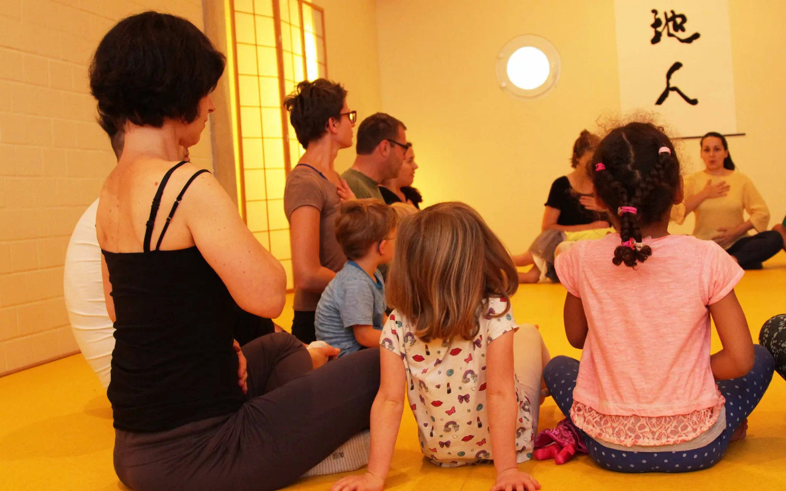 Eltern und Kinder sitzen gemeinsam in einem Kreis und spüren ihre Atmung.