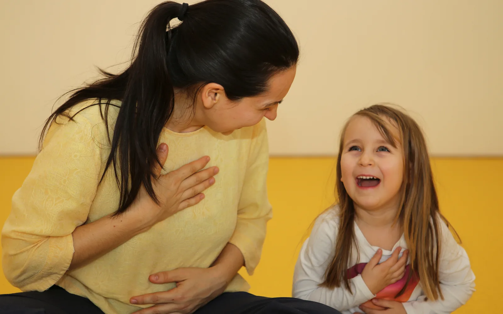 Marta und ein Kind lachen während einer gemeinsamen Yogaübung.