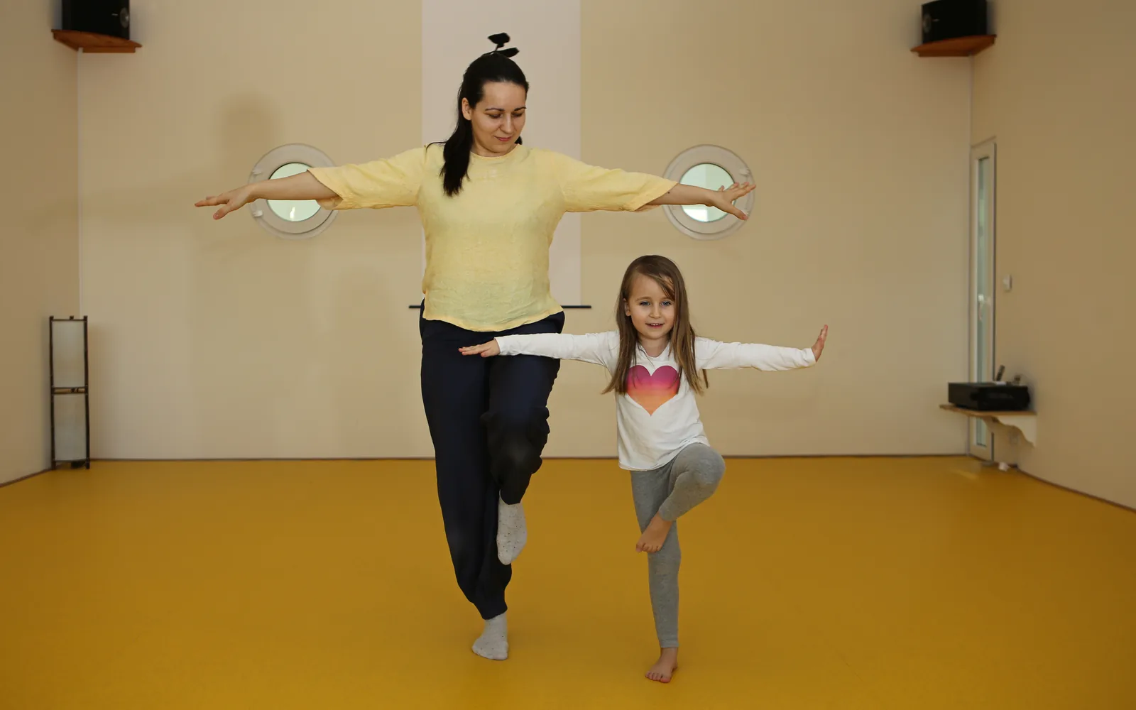 Marta und ein Kind balancieren gemeinsam mit ausgebreiteten Armen.