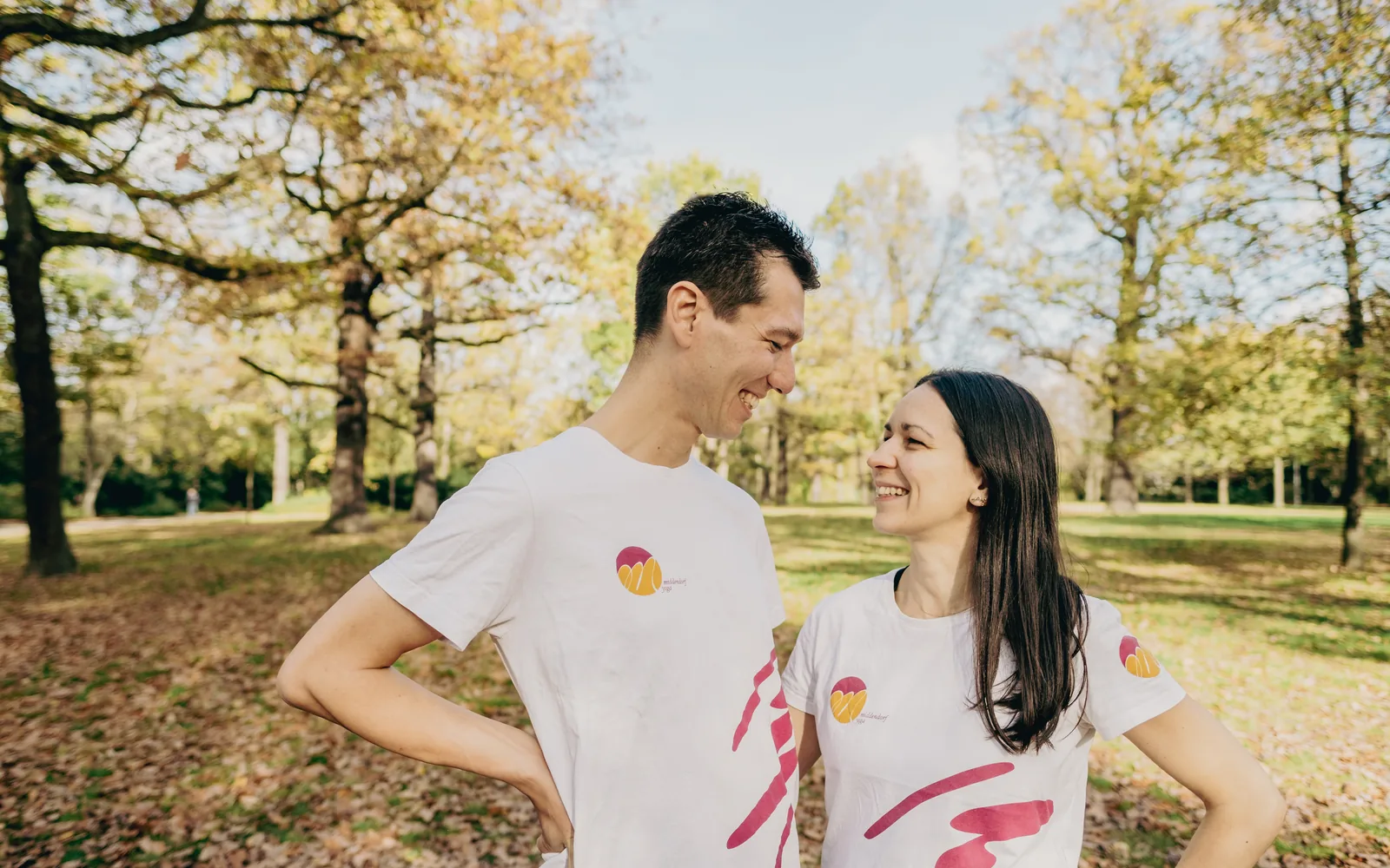 Manuel und Marta stehen einander zugewandt im Park.